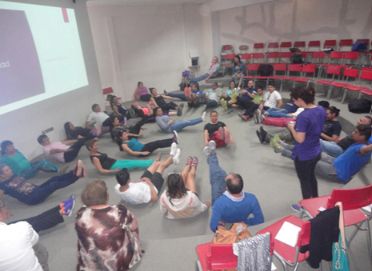 Equipo de salud realizando un ejercicio de autocuidado en auditorio